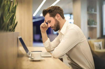 Man looking frustrated in front of his computer at the office